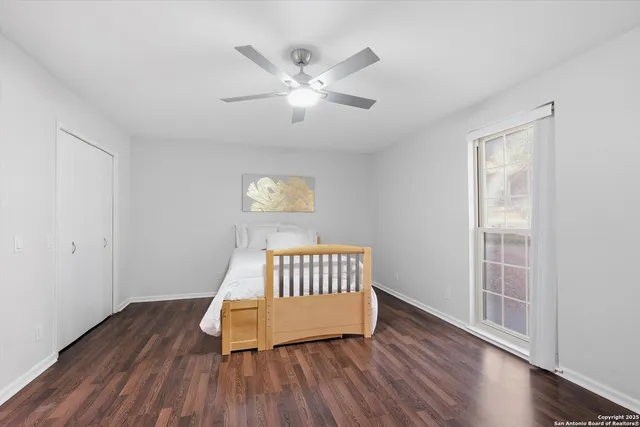 an empty room with wooden floor fan and windows