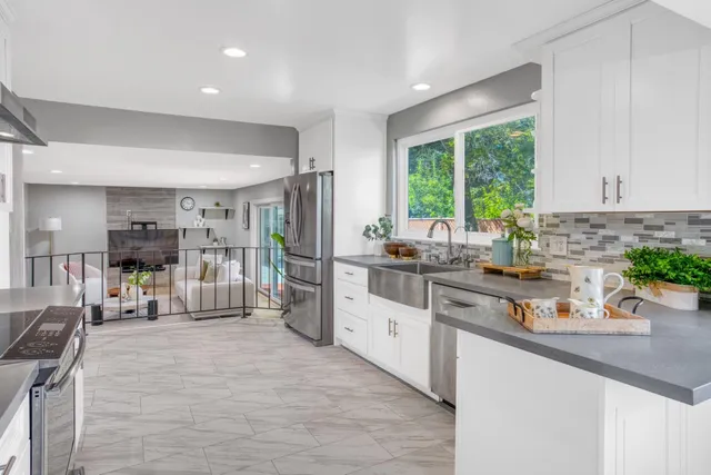 a kitchen with stainless steel appliances granite countertop a refrigerator a sink dishwasher and white cabinets with wooden floor