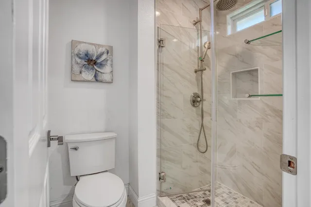 a white toilet sitting next to a shower
