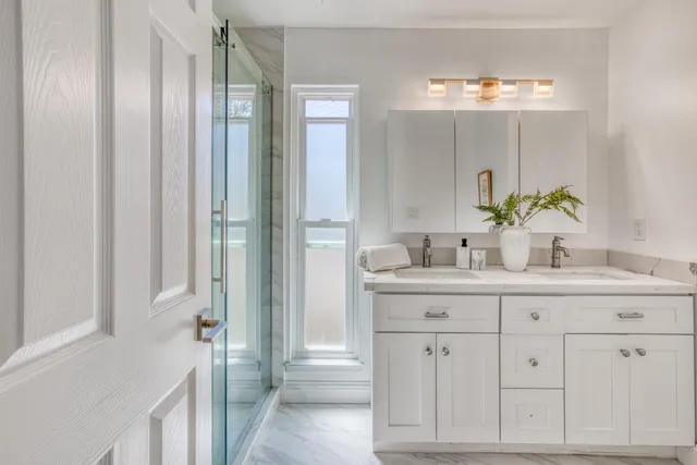 a bathroom with a granite countertop sink mirror and cabinets