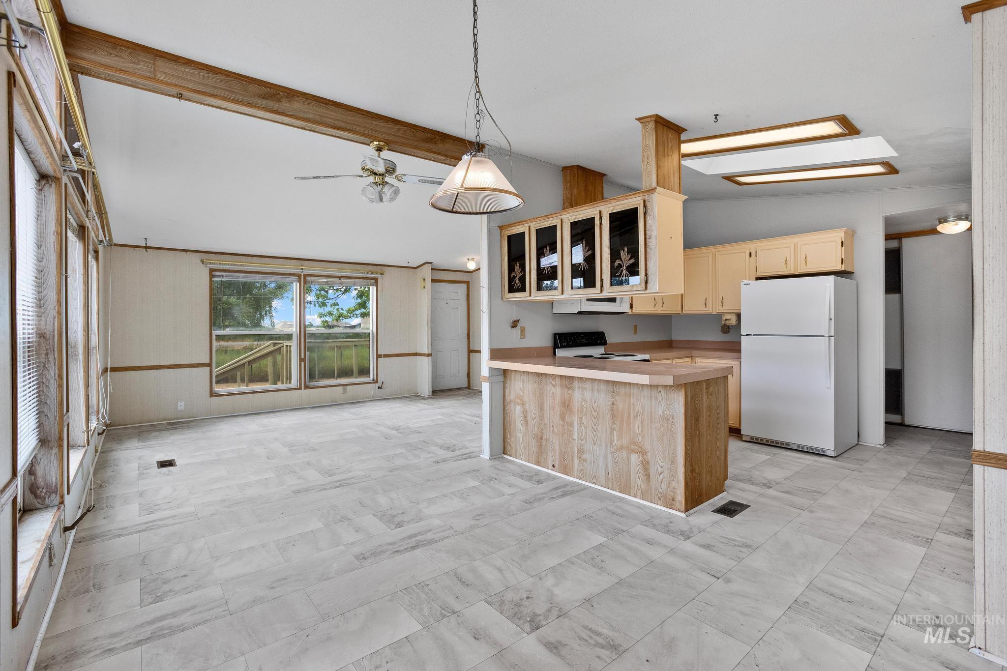 3680 South Mill Road Emmett, ID 83617 - Photo 15 of 38 Open-concept living space featuring wood-finish flooring, a kitchen island with storage, light wood cabinetry, and a ceiling fan with integrated lighting