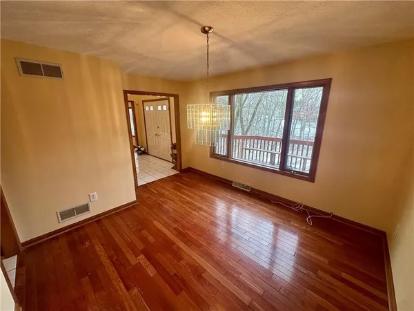 a view of an empty room with window and wooden floor