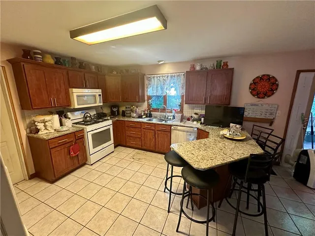 a kitchen with stainless steel appliances granite countertop a sink dishwasher a stove a refrigerator with a dining table and chairs