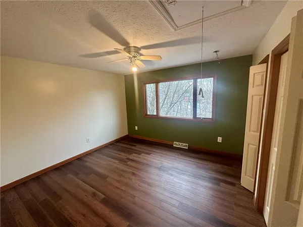 an empty room with wooden floor fan and windows