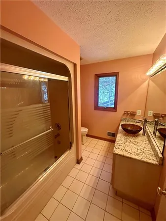 a bathroom with a granite countertop sink a toilet and shower