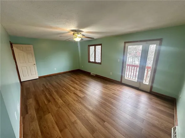 a view of an empty room with window and wooden floor