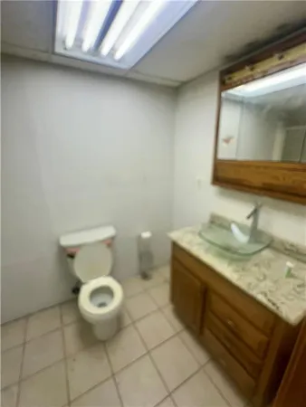 a bathroom with a granite countertop sink and a toilet