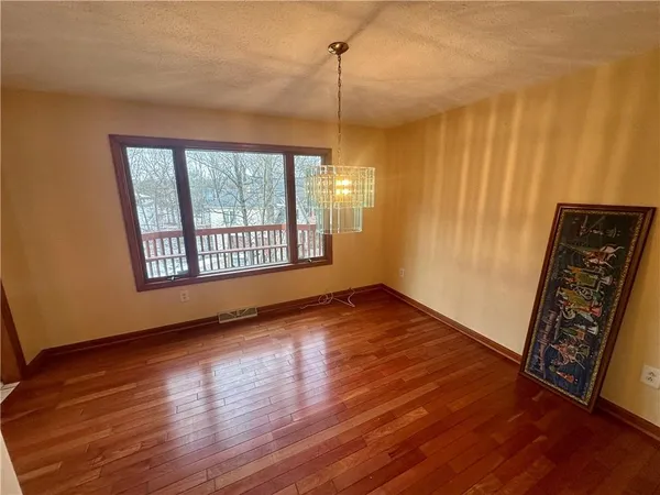 a view of an empty room with window and wooden floor