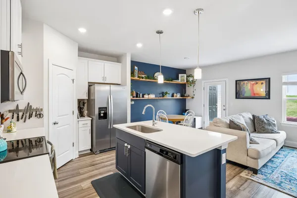 a kitchen with kitchen island a refrigerator stove a sink and dishwasher with wooden floor