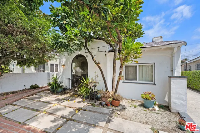 a view of a patio with table and chairs potted plants and large tree