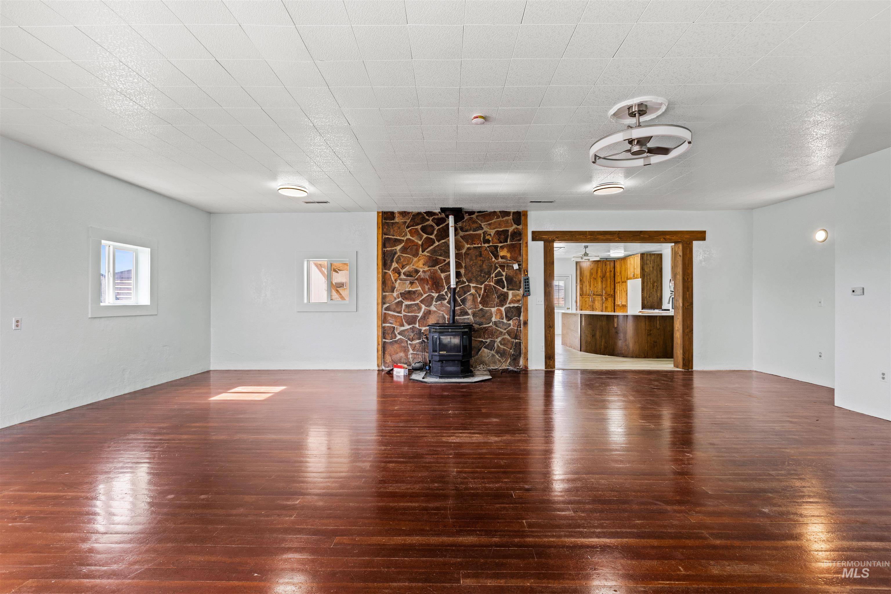5168 South Jump Creek Road Marsing, ID 83639 - Photo 11 of 40 Unfurnished living room with a wood stove, dark wood-style floors, and a ceiling fan