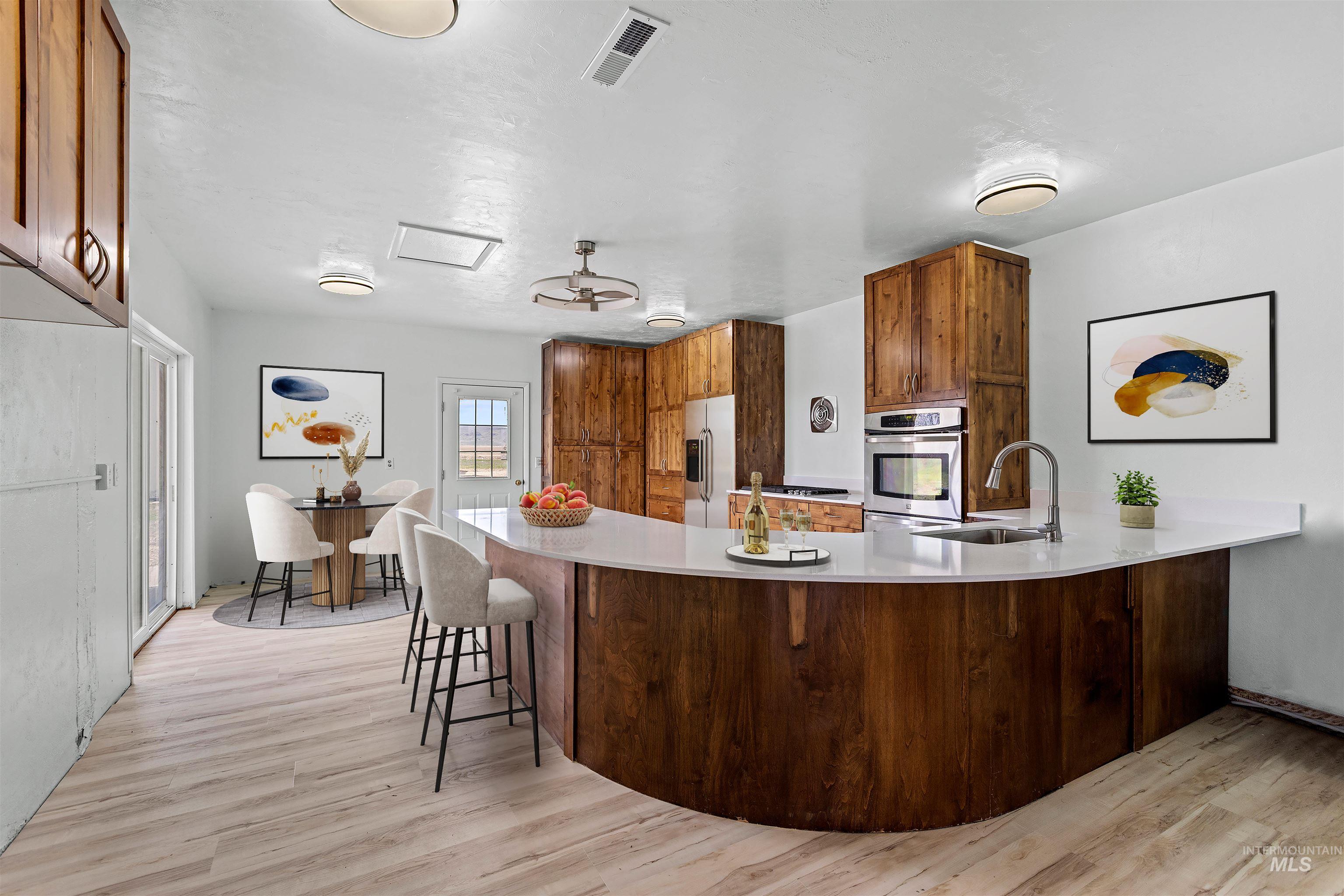 5168 South Jump Creek Road Marsing, ID 83639 - Photo 14 of 40 Kitchen featuring a peninsula, a kitchen breakfast bar, light wood-style flooring, wood finish cabinets, and stainless steel appliances