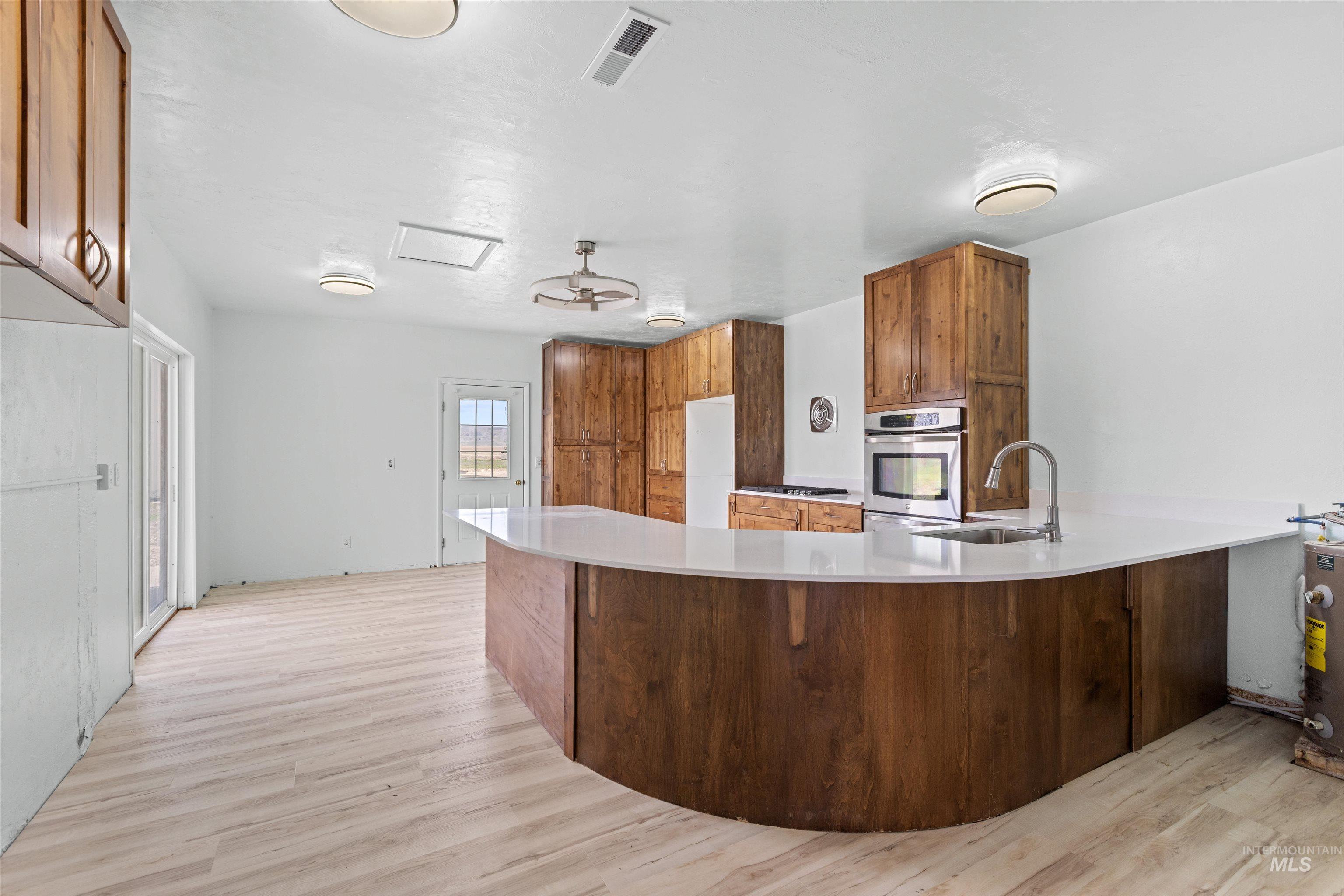 5168 South Jump Creek Road Marsing, ID 83639 - Photo 15 of 40 Kitchen with a peninsula, wood finish cabinets, light wood finished floors, oven, and a kitchen bar