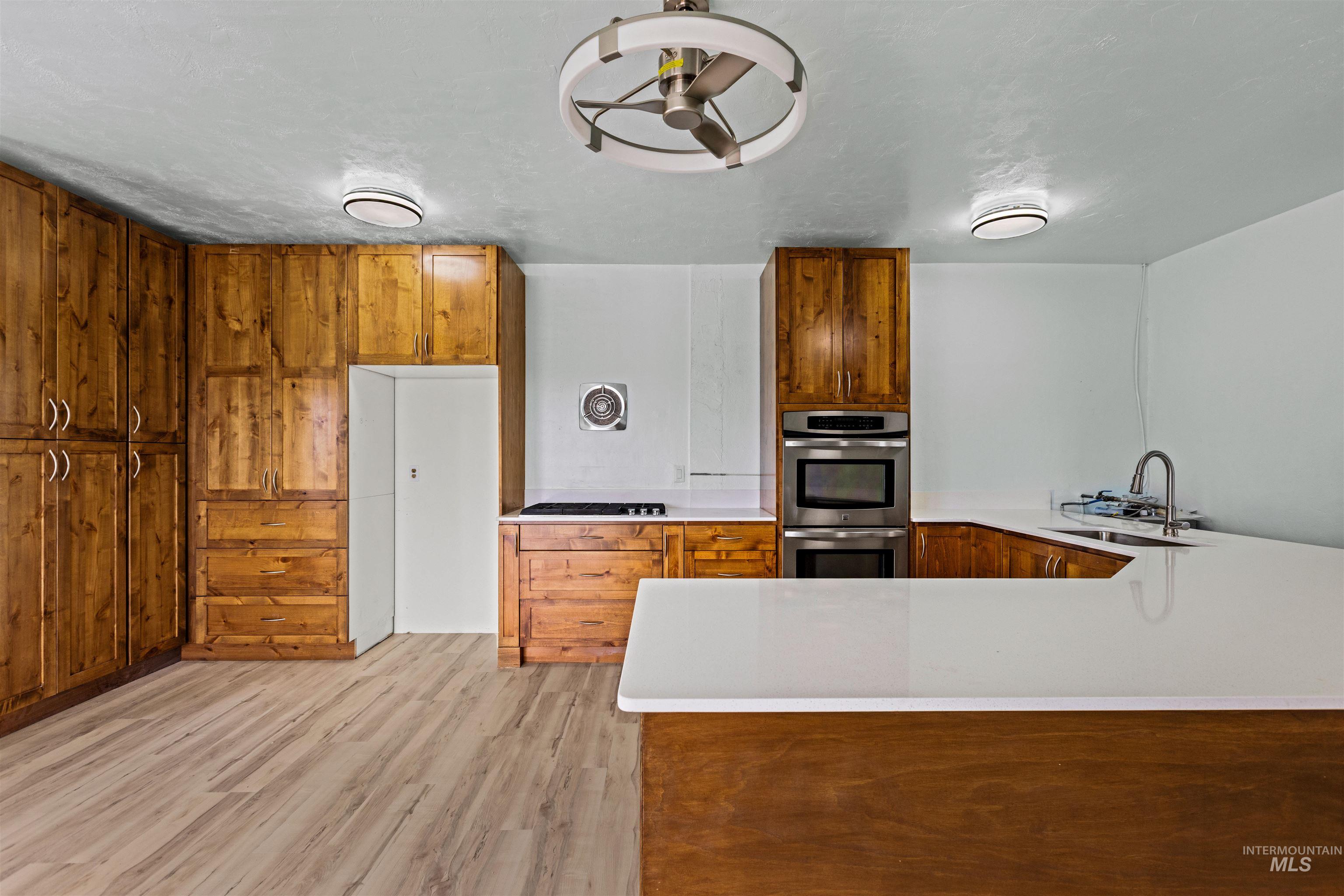 5168 South Jump Creek Road Marsing, ID 83639 - Photo 16 of 40 Kitchen with wood finish cabinets, a peninsula, stainless steel appliances, and light wood finished floors