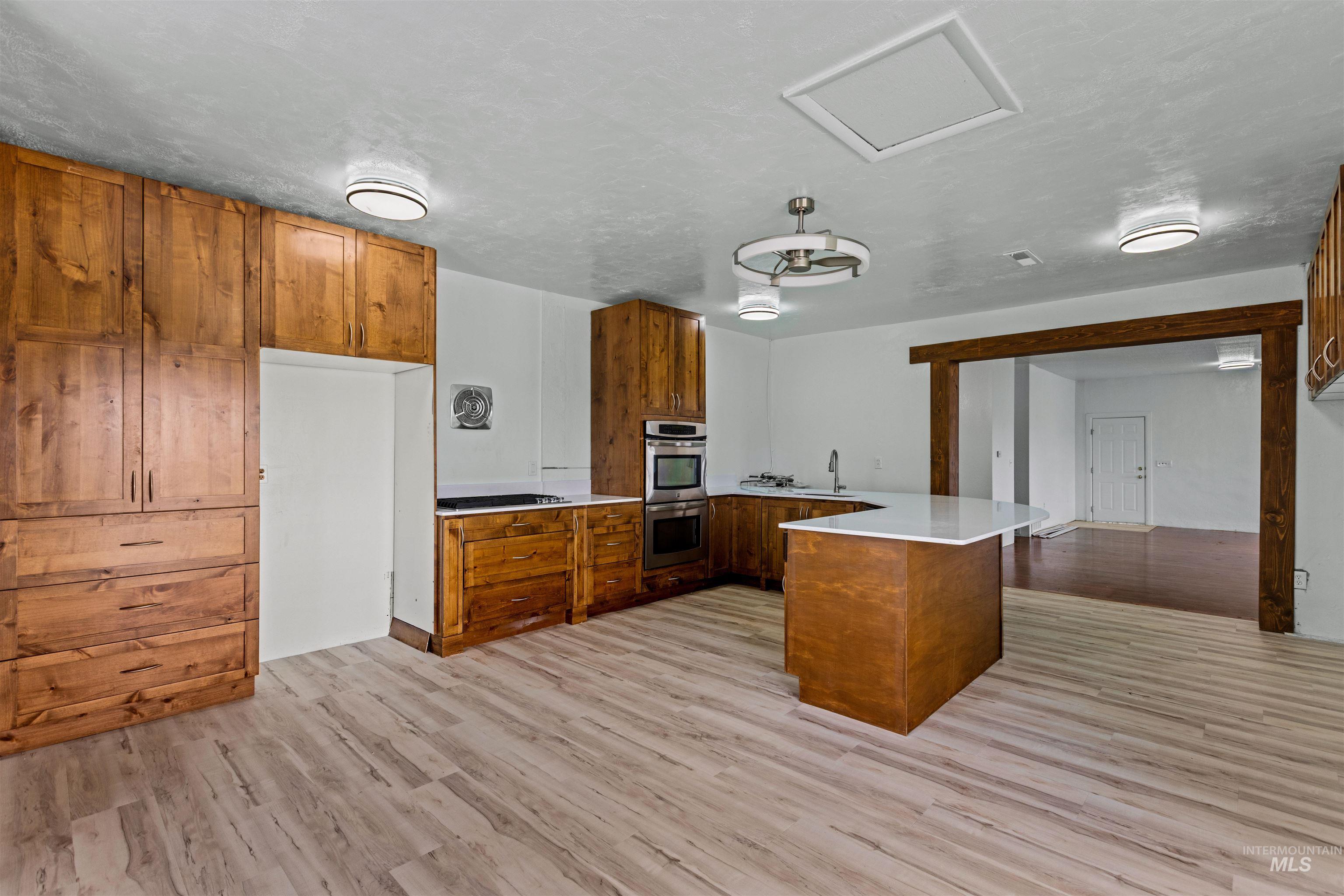 5168 South Jump Creek Road Marsing, ID 83639 - Photo 17 of 40 Kitchen with a peninsula, wood finish cabinets, light wood finished floors, double oven, and light stone countertops