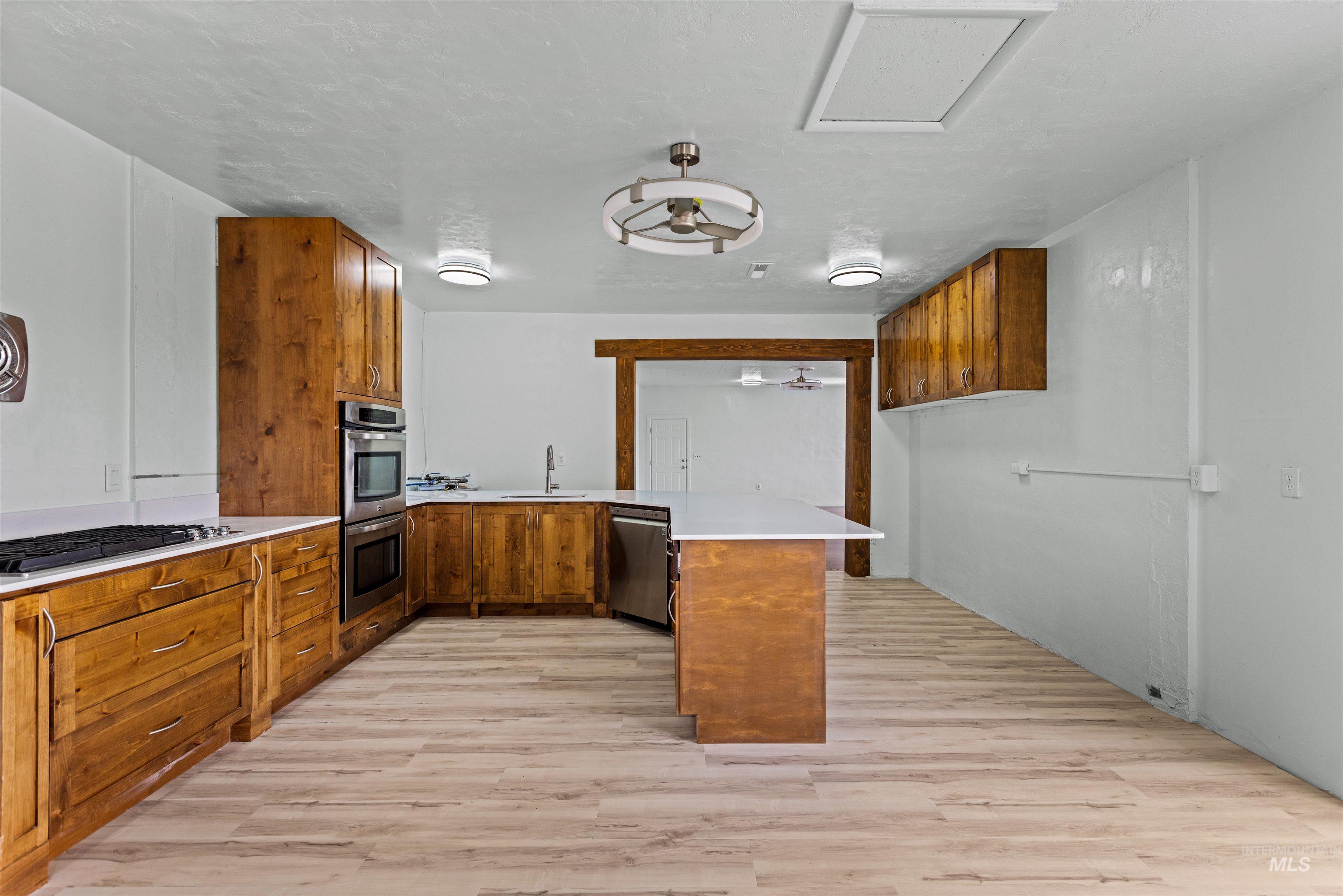 5168 South Jump Creek Road Marsing, ID 83639 - Photo 18 of 40 Kitchen with wood finish cabinets, a peninsula, light wood finished floors, stainless steel appliances, and a ceiling fan