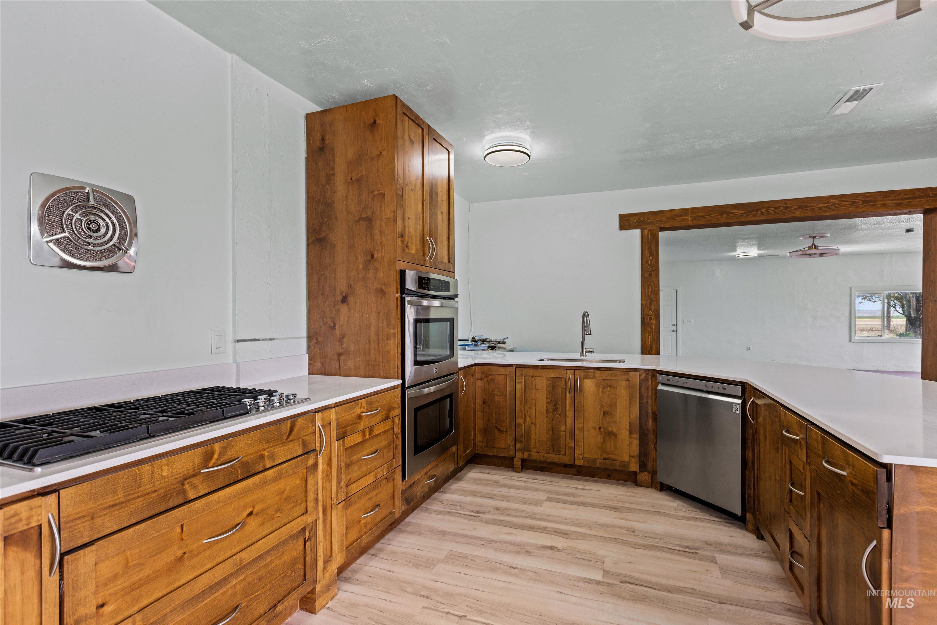 5168 South Jump Creek Road Marsing, ID 83639 - Photo 19 of 40 Kitchen with a peninsula, wood finish cabinets, stainless steel appliances, and light wood-style flooring