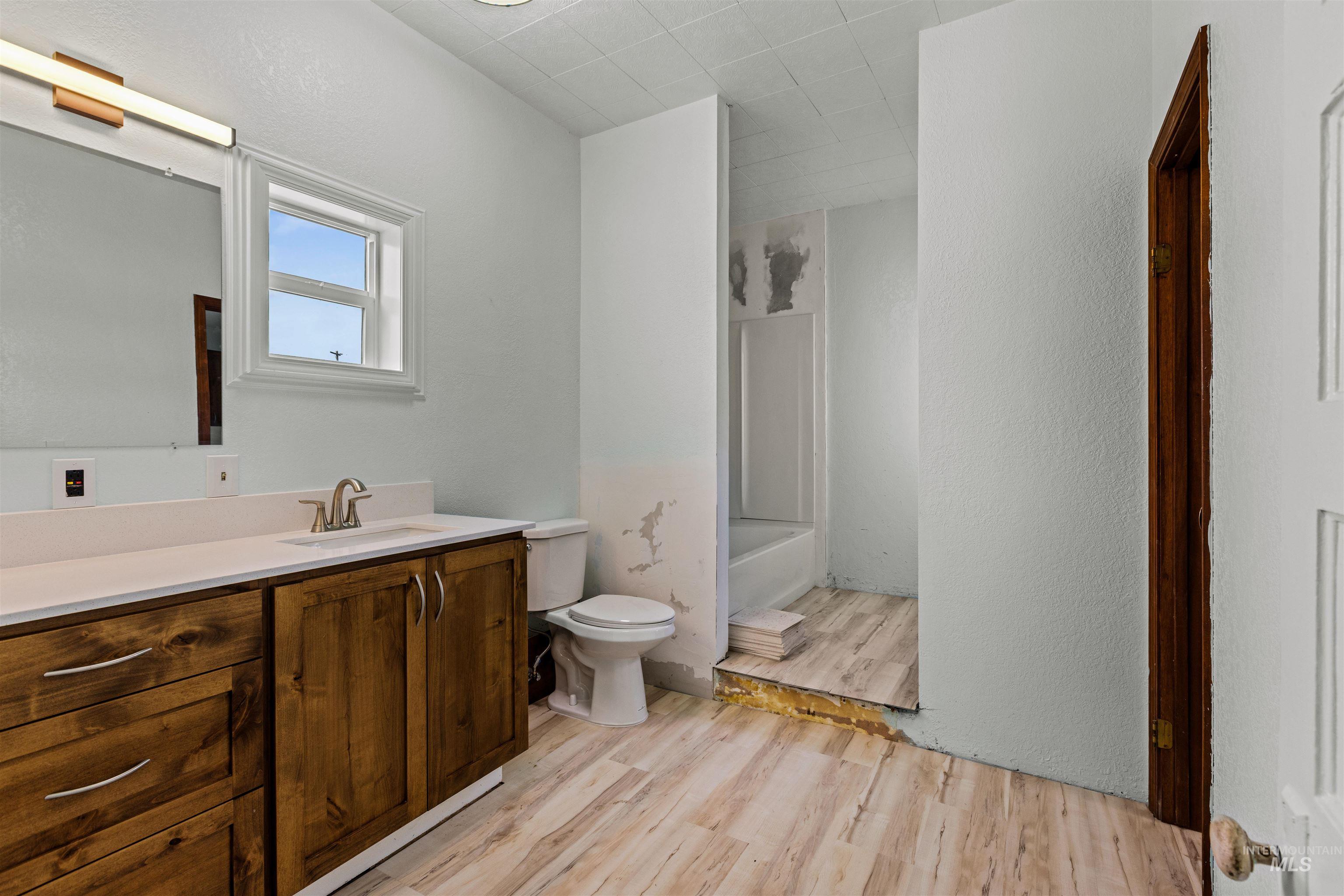 5168 South Jump Creek Road Marsing, ID 83639 - Photo 26 of 40 Bathroom featuring light wood finished floors, vanity, a textured wall, and tub / shower combination