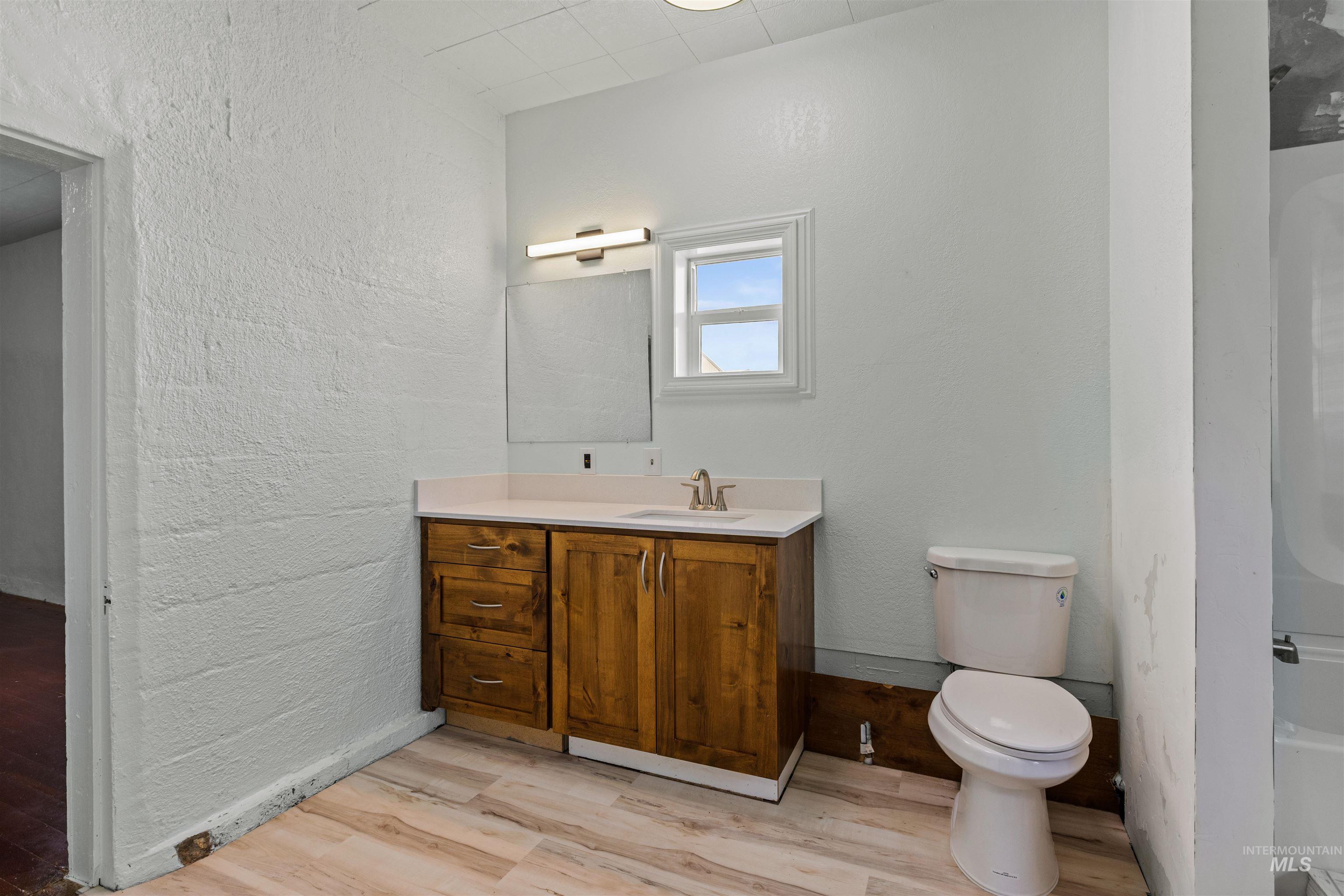 5168 South Jump Creek Road Marsing, ID 83639 - Photo 27 of 40 Bathroom featuring vanity, light wood-style flooring, a textured wall, and shower combination