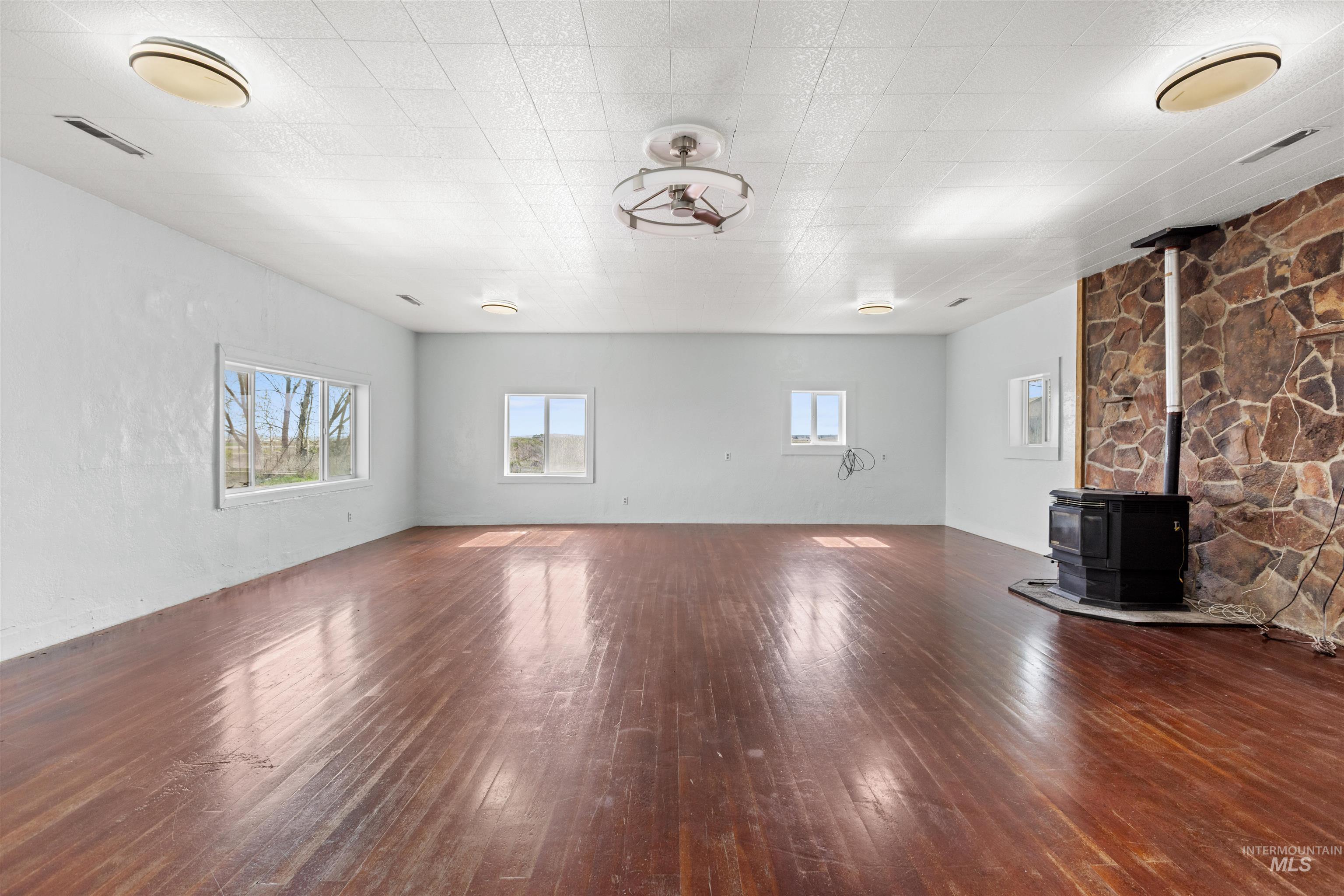 5168 South Jump Creek Road Marsing, ID 83639 - Photo 9 of 40 Unfurnished living room featuring a wood stove and dark wood-style floors