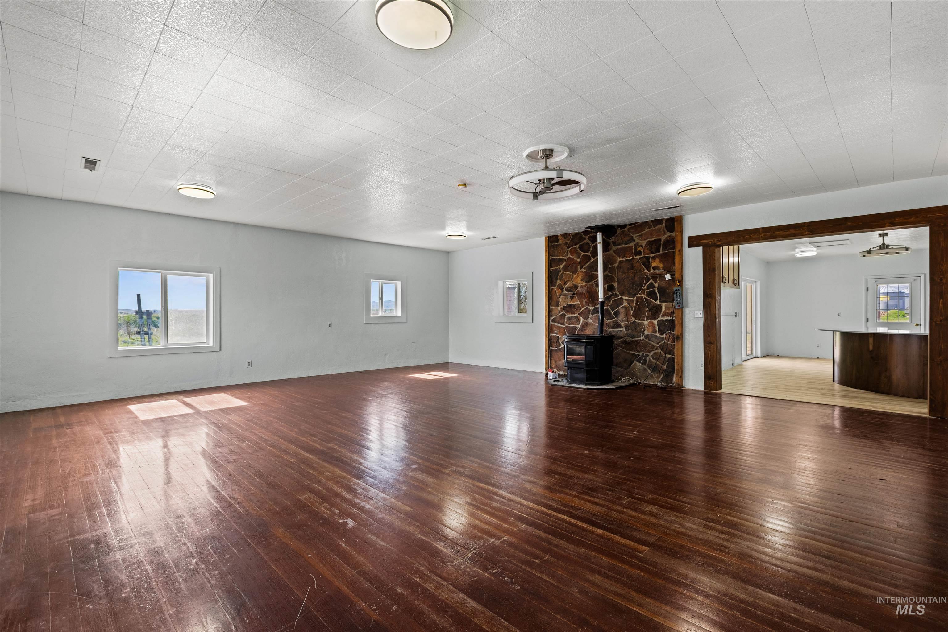 5168 South Jump Creek Road Marsing, ID 83639 - Photo 10 of 40 Unfurnished living room featuring hardwood / wood-style flooring, a wood stove, and ceiling fan