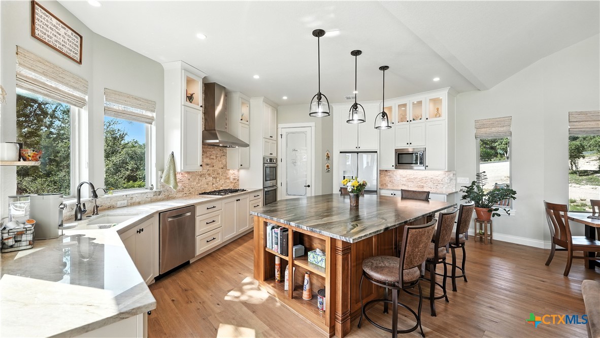 134 Stallion Estates Drive Spring Branch, TX 78070 - Photo 19 of 48 a large kitchen with stainless steel appliances a table chairs sink and wooden floor
