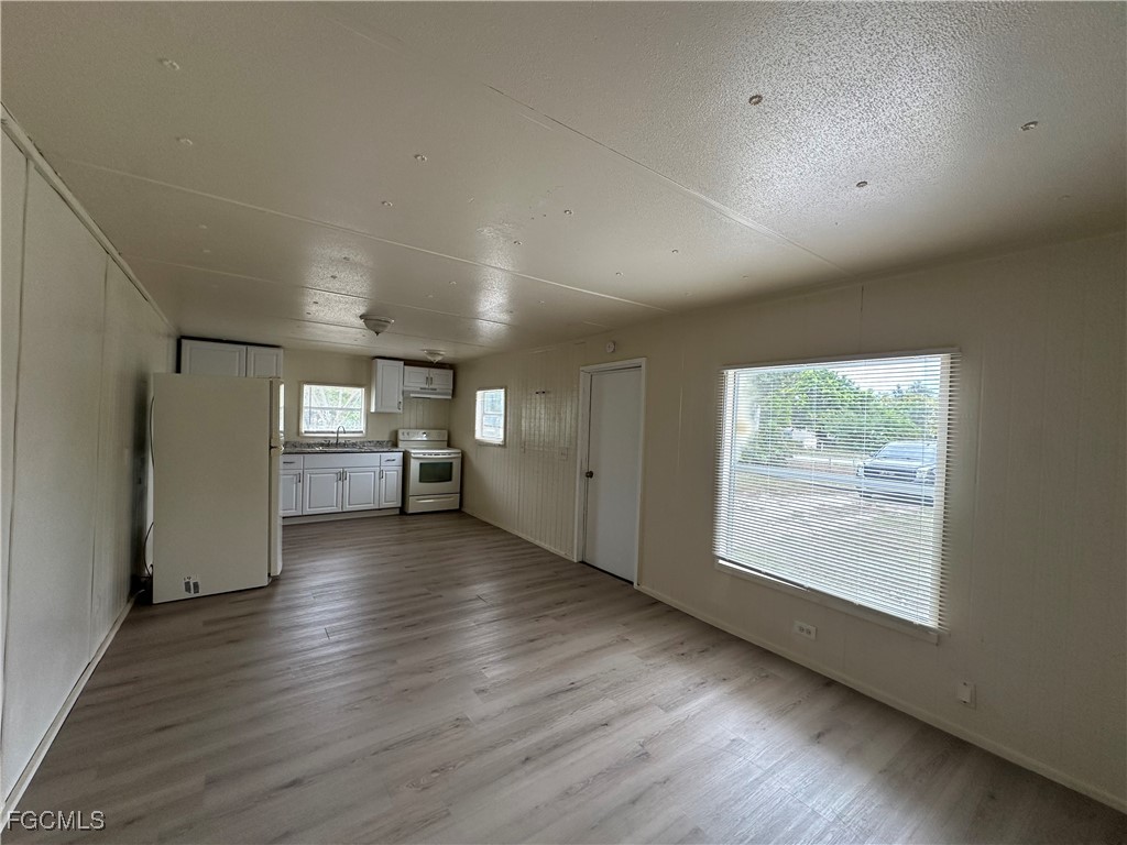 8376 Nault Road North Fort Myers, FL 33917 - Photo 3 of 10 an empty room with wooden floor cabinet and windows