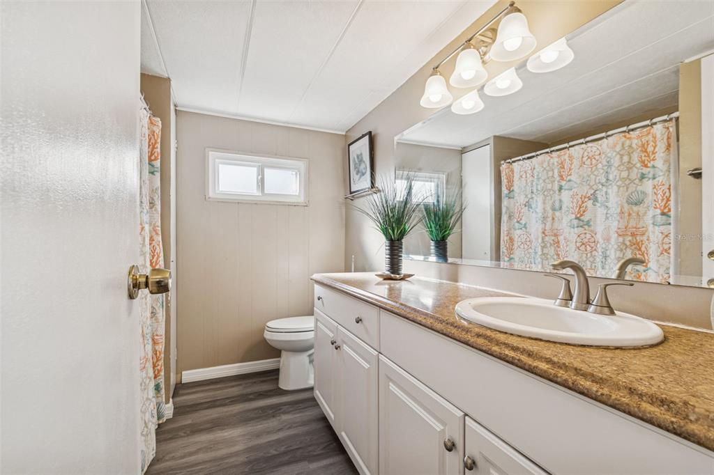 86 Pindo Palm Street West Largo, FL 33770 - Photo 14 of 45 a bathroom with a granite countertop sink a toilet and a mirror