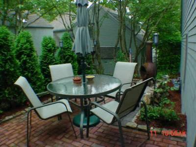 Undisclosed Address Mashpee, MA 02649 - Photo 1 of 3 a backyard with a table and chairs and potted plants