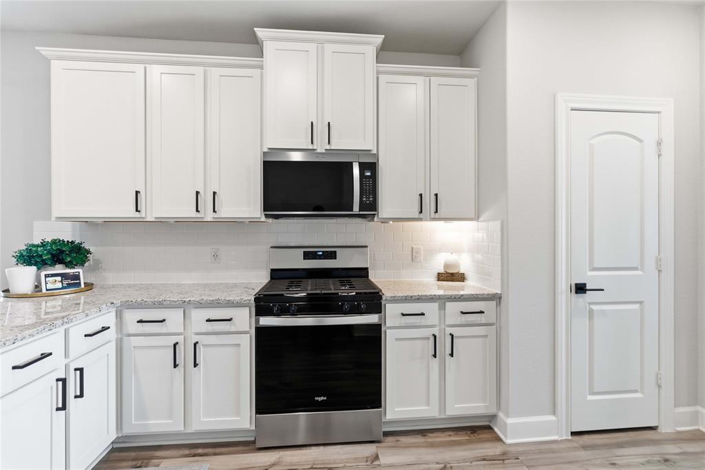1012 Calhoun Drive Anna, TX 75409 - Photo 11 of 39 Kitchen featuring white shaker-style cabinetry, granite countertops, subway tile backsplash, stainless steel range, and wood-finish flooring