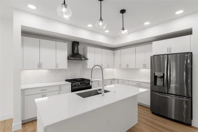 a kitchen with stainless steel appliances granite countertop a sink a stove a refrigerator and cabinets