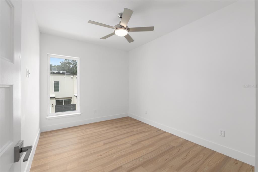 3288 Southwest 49th Terrace Gainesville, FL 32608 - Photo 42 of 71 an empty room with wooden floor ceiling fan and windows