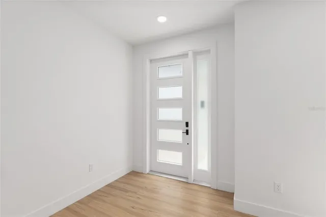 a view of an empty room with window and wooden floor
