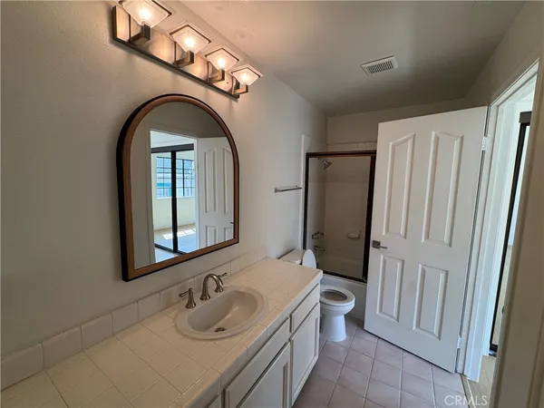 a bathroom with a granite countertop sink toilet and shower a mirror