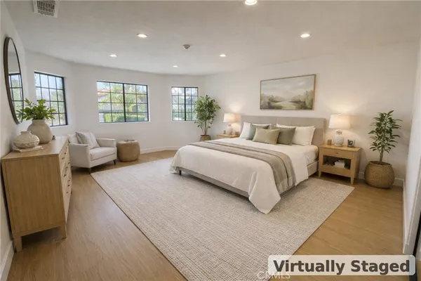 a spacious bedroom with a bed a couch and a large window