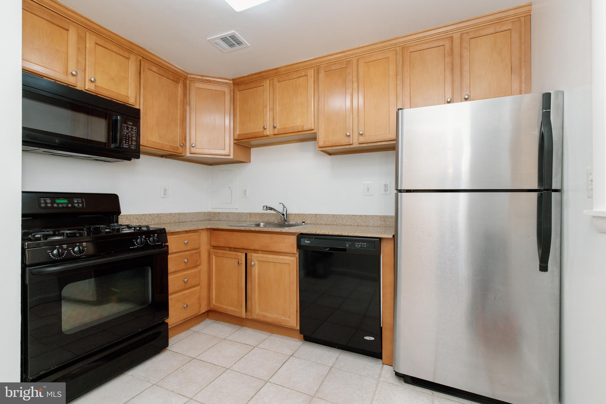 10570 Main Street, Unit 424 Fairfax, VA 22030 - Photo 8 of 18 a white refrigerator freezer and a stove sitting inside of a kitchen with granite countertop stainless steel appliances