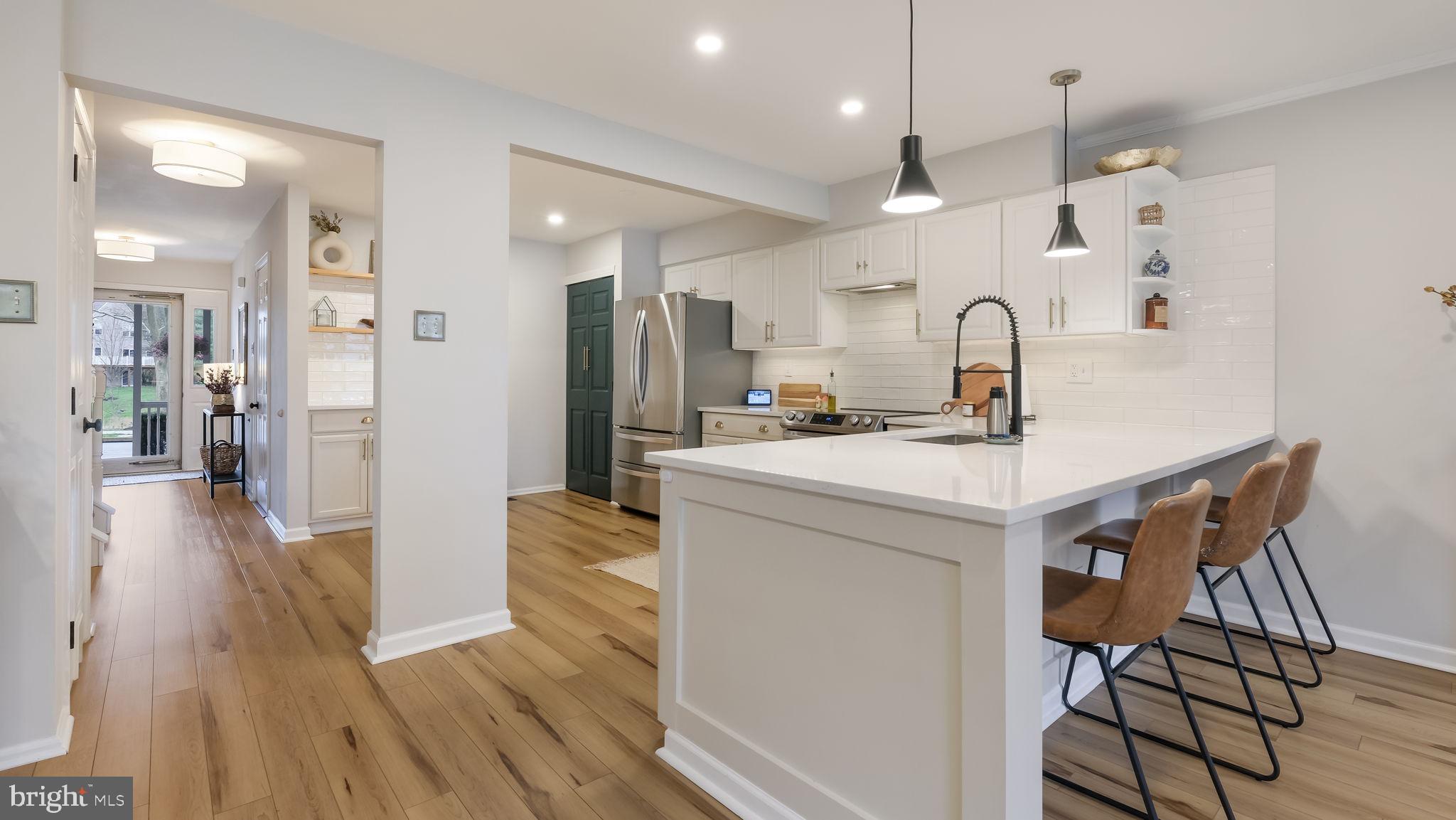 a kitchen with stainless steel appliances a refrigerator a sink dishwasher and a stove with wooden floor