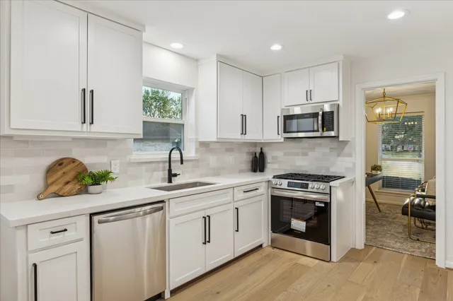 a kitchen with stainless steel appliances granite countertop a sink a stove a microwave a refrigerator a counter space and cabinets