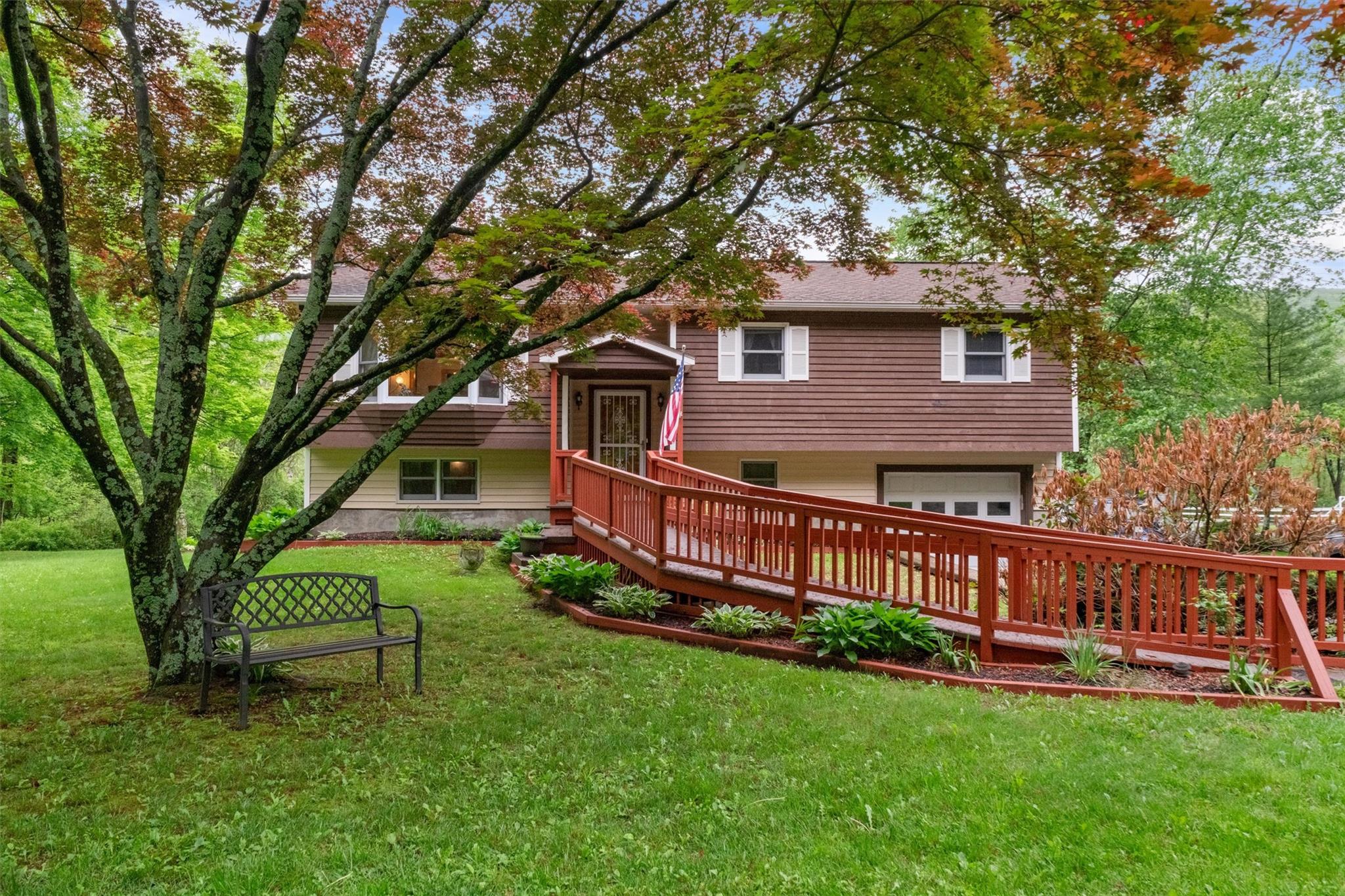 a view of a house with a yard deck and a large tree
