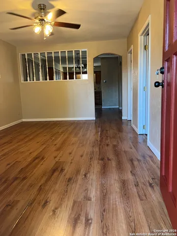 a view of an empty room with wooden floor and a window
