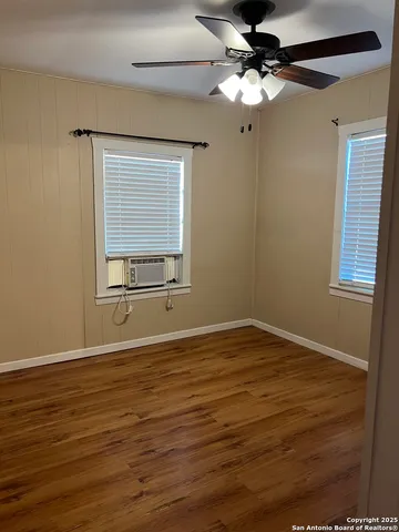 a view of an empty room with a window and wooden floor