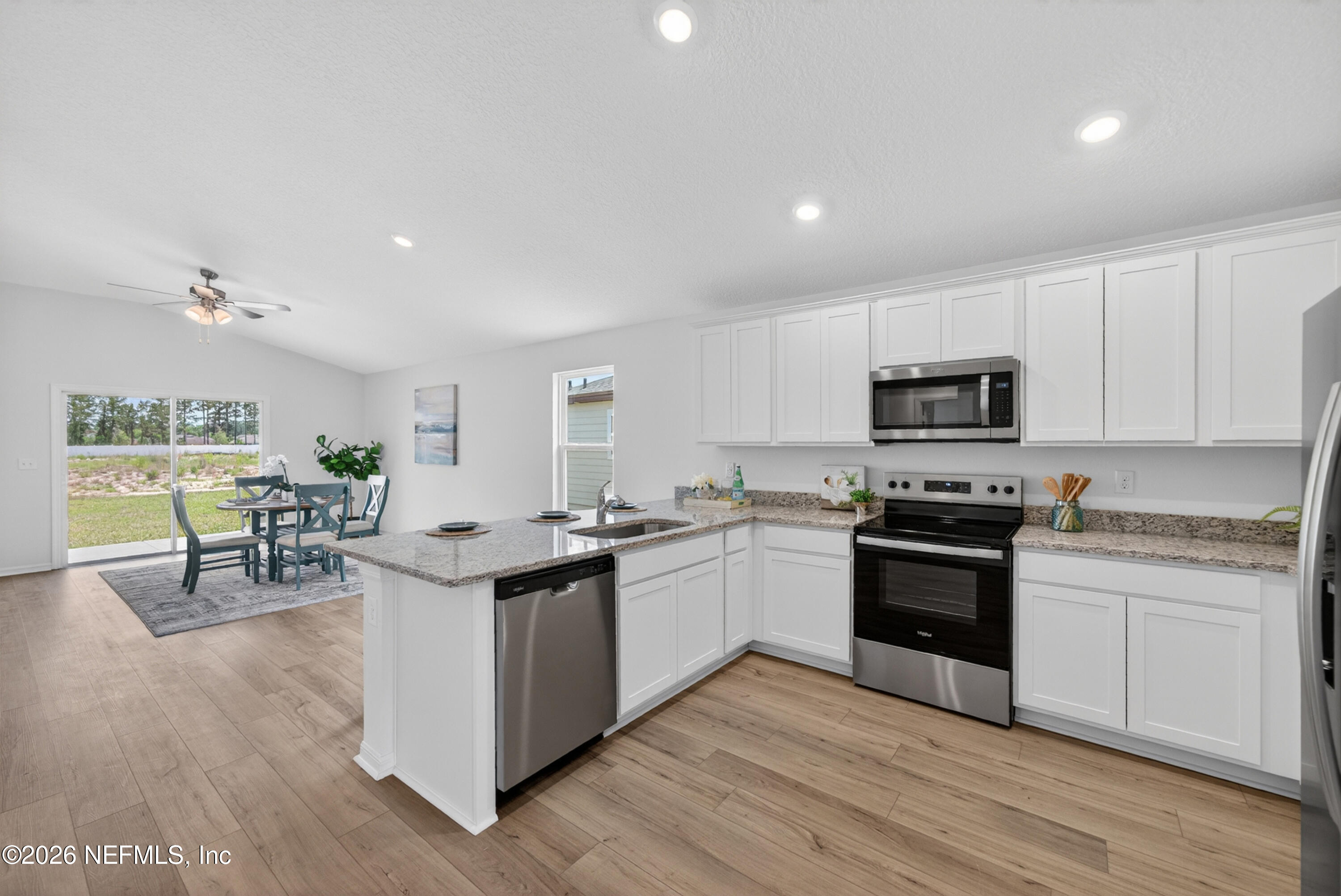 6855 Myrtle Oak Road Jacksonville, FL 32219 - Photo 14 of 27 a kitchen with stainless steel appliances granite countertop a stove top oven a sink dishwasher and white cabinets with wooden floor