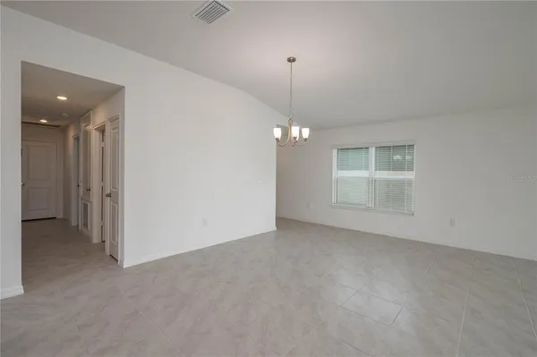 an empty room with chandelier fan and windows