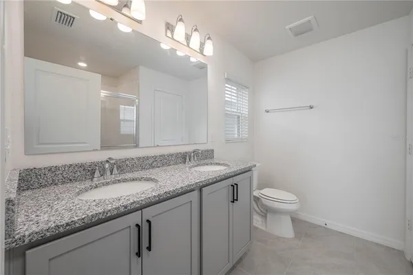 a bathroom with a granite countertop sink a toilet and a mirror