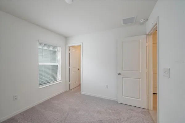 a view of an empty room with closet and a window
