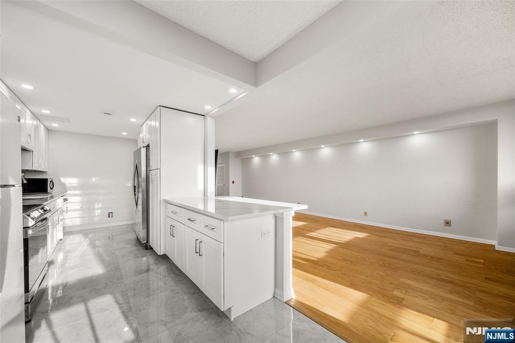 800 Palisade Avenue, Unit 1804 Fort Lee, NJ 07024 - Photo 7 of 23 a large kitchen with cabinets and a wooden floor