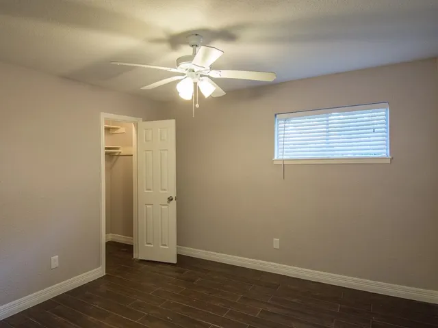 an empty room with wooden floor closet and windows
