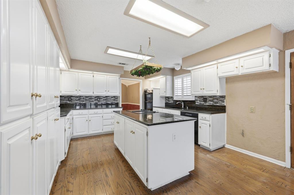 7260 Hudson Cemetery Road Mansfield, TX 76063 - Photo 18 of 40 Spacious kitchen featuring an expansive center island, white cabinetry with brass-finish hardware, dark countertops, and wood-finish flooring