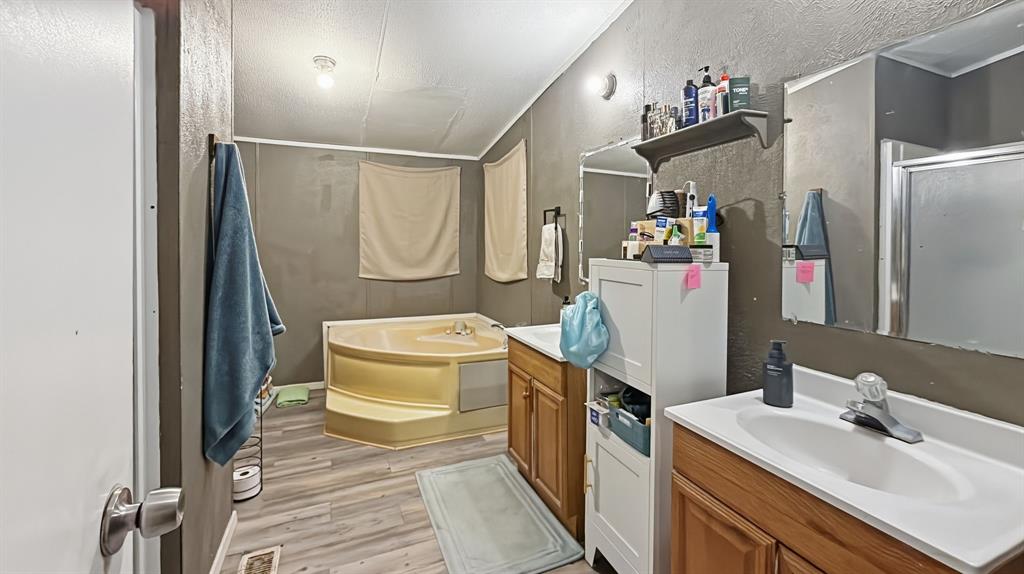 185 Private Road 4437 Rhome, TX 76078 - Photo 10 of 28 Bathroom featuring a step-up soaking tub, dual vanity sinks, wood-finish flooring, and a glass-enclosed shower