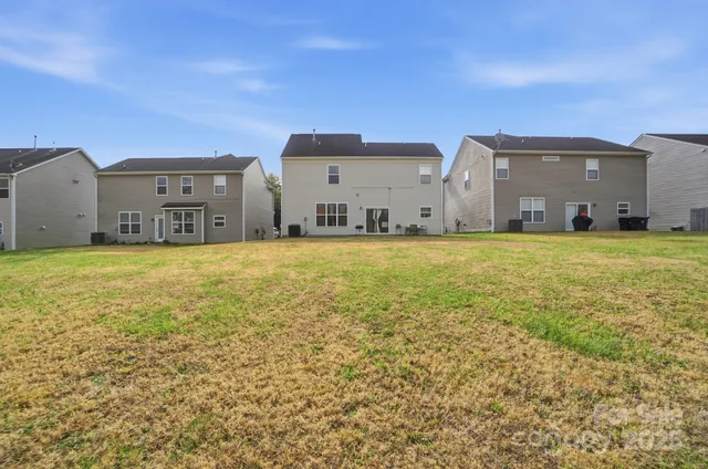 a view of a large pool with lawn chairs and a large tree